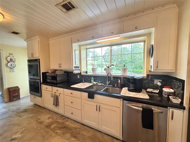 a kitchen with granite countertop a sink and white cabinets