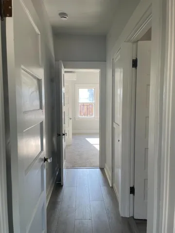 a view of a hallway with wooden floor and closet area