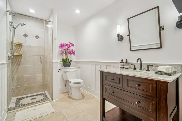 a bathroom with a granite countertop shower sink mirror and toilet