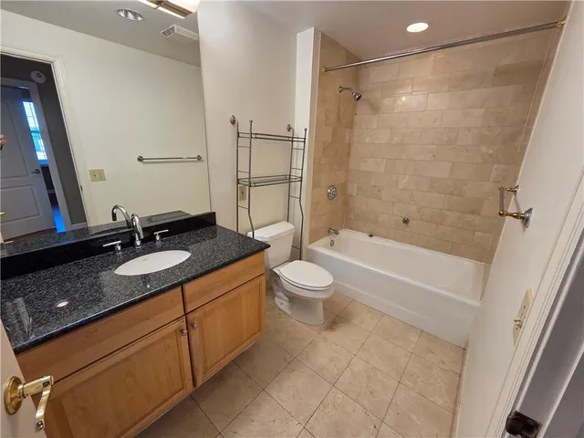 a bathroom with a granite countertop sink a toilet a mirror and shower