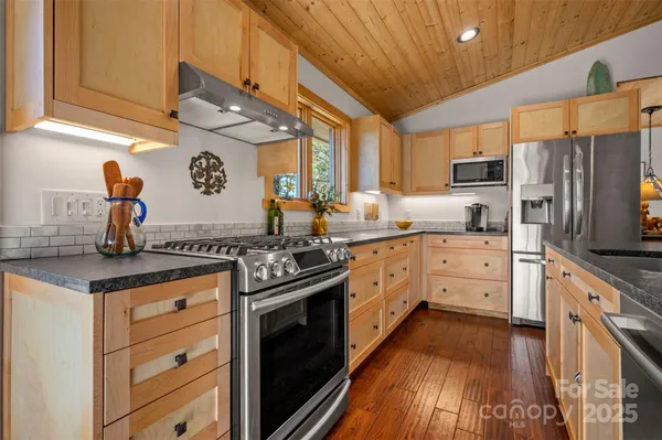 a kitchen with stainless steel appliances granite countertop a stove a sink and a refrigerator