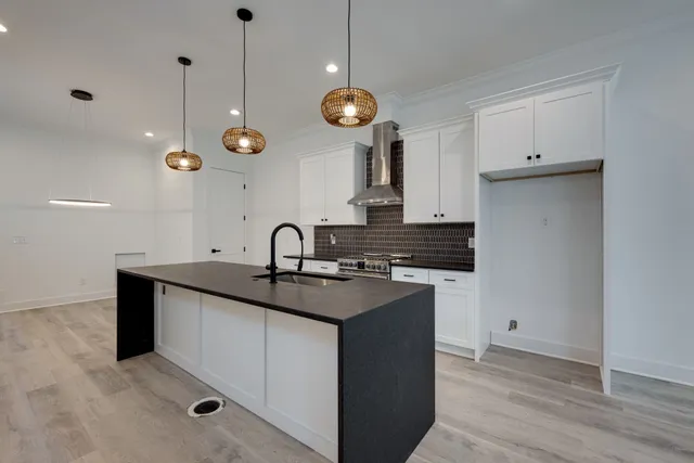 a kitchen with stainless steel appliances granite countertop a sink a stove and a wooden floors