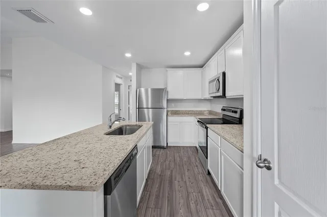 a kitchen with kitchen island granite countertop a sink stove refrigerator and cabinets