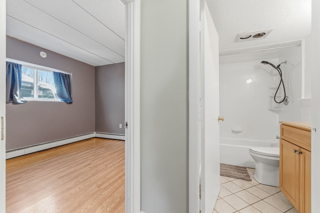 1011 Main Street, Unit 5 Woburn, MA 01801 - Photo 11 of 26 a bathroom with a granite countertop toilet and a shower