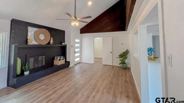a view of an empty room with wooden floor and a fireplace