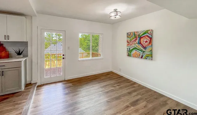 a view of an empty room with window and wooden floor