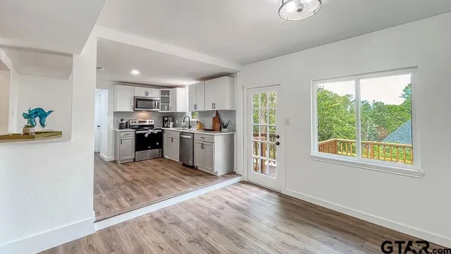 a kitchen with stainless steel appliances granite countertop a stove top oven a sink and dishwasher a refrigerator with wooden floor