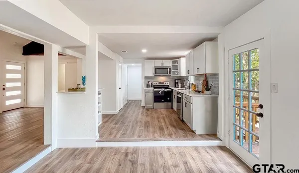 a kitchen with stainless steel appliances granite countertop a refrigerator a stove top oven a sink and dishwasher with wooden floor
