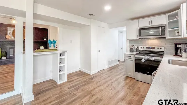 a kitchen with stainless steel appliances a stove top oven a sink and a refrigerator