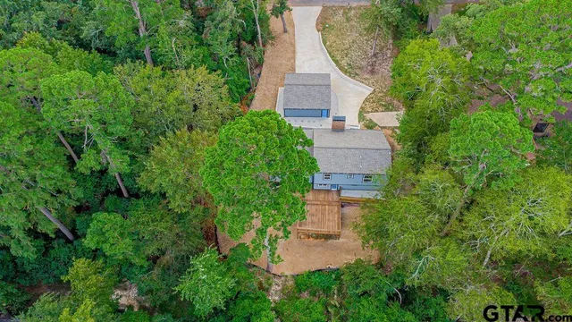 an aerial view of residential house with outdoor space and trees all around
