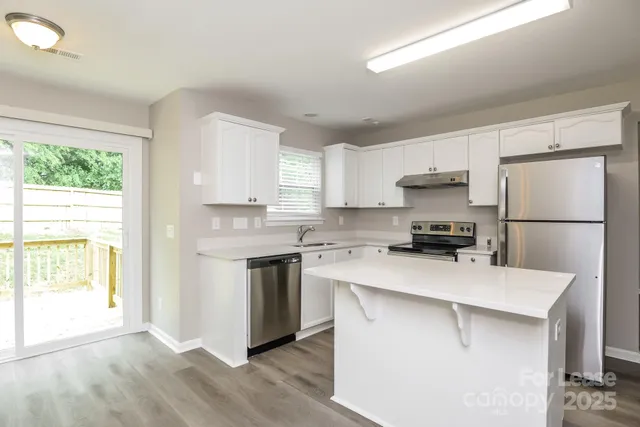 a kitchen with a sink a stove a refrigerator a center island and a window