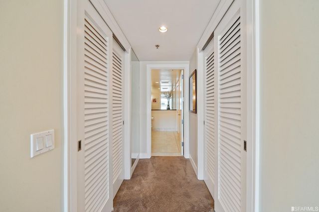 a view of a hallway with wooden floor and a bathroom