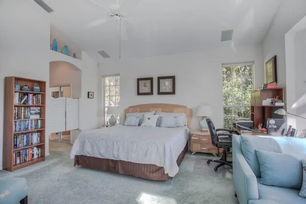 a bedroom with a bed a book shelf and a window