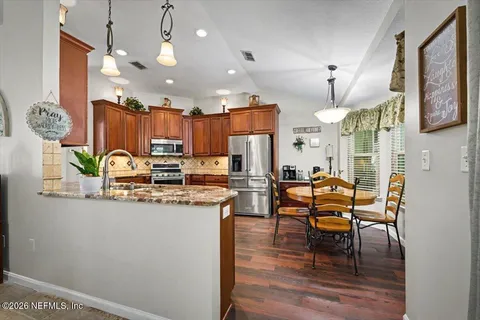 a kitchen with stainless steel appliances granite countertop wooden cabinets a stove a sink and a refrigerator