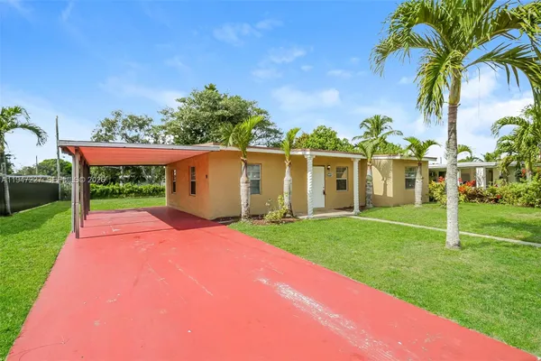 a view of a house with a big yard plants and palm trees