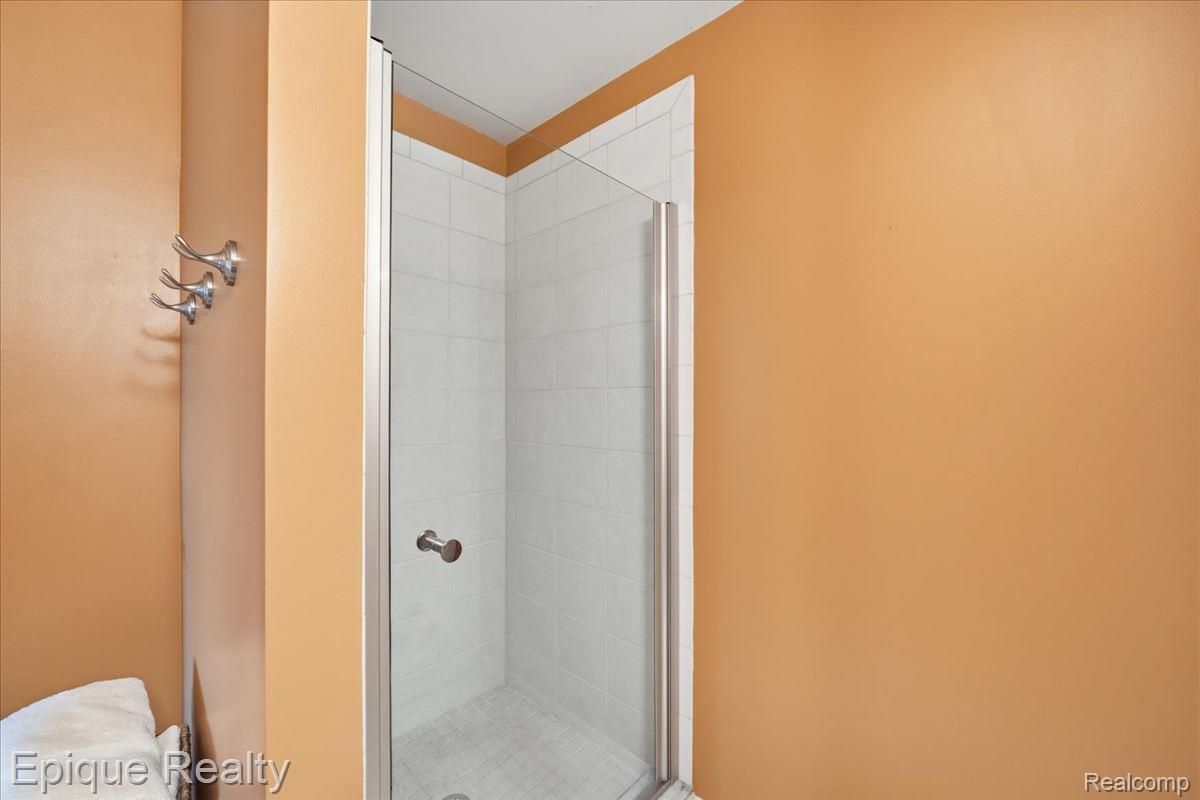 26 Kirks Court Rochester, MI 48309 - Photo 33 of 44 Shower enclosure featuring a clear glass door, chrome hardware, white tile surround, and a coordinating tiled shower pan