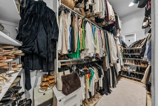 a view of walk in closet with clothes and shoes