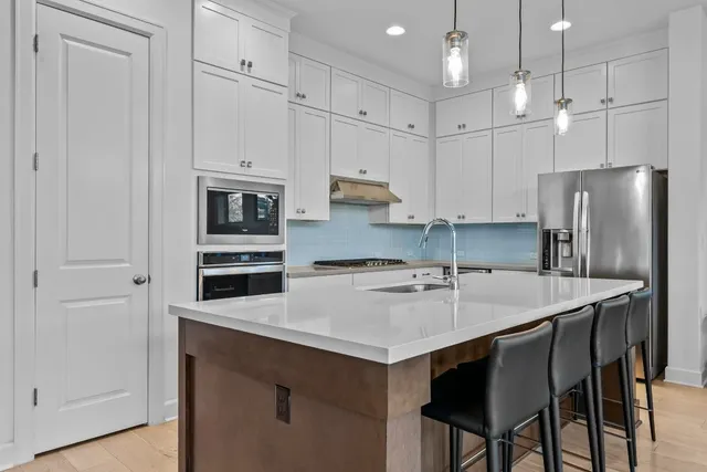 a kitchen with stainless steel appliances a table chairs refrigerator and cabinets