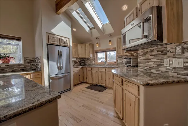 a kitchen with stainless steel appliances granite countertop a sink a stove and a refrigerator