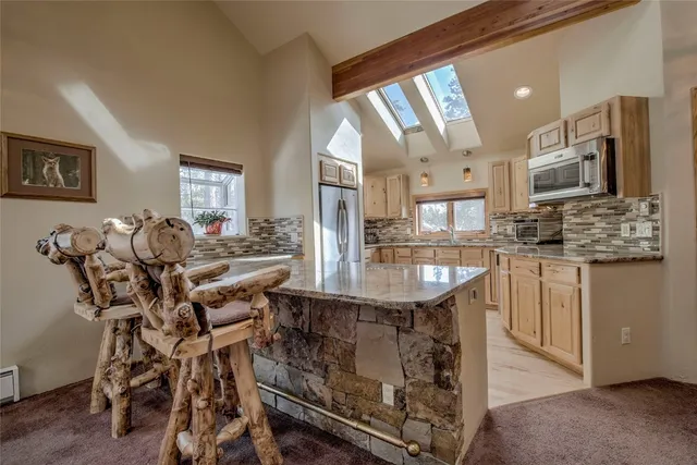 a kitchen with kitchen island granite countertop a table chairs sink and cabinets