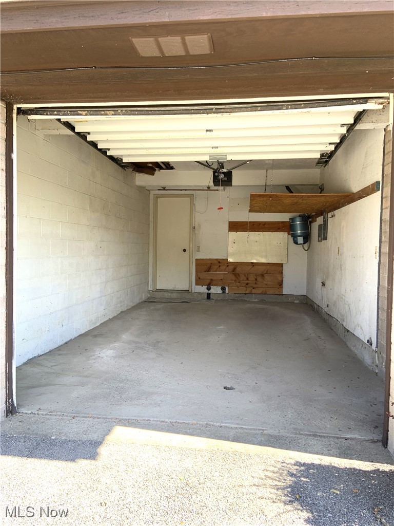 9956 Johnnycake Ridge Road, Unit D9 Painesville, OH 44077 - Photo 4 of 37 Garage with concrete block wall and a garage door opener
