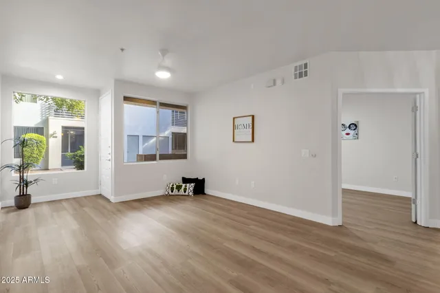 a view of an empty room with wooden floor and a window
