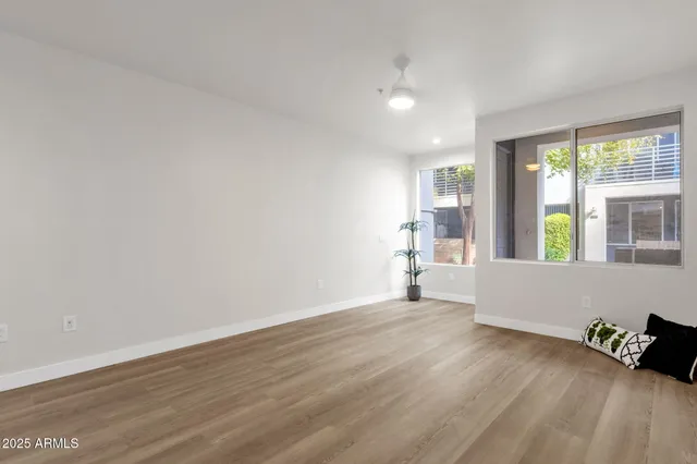 a view of an empty room with wooden floor and a window