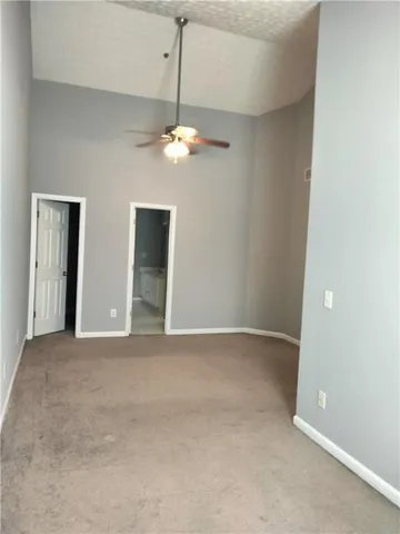 an empty room with chandelier fan and windows
