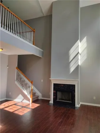 a view of an empty room with wooden floor stairs and a fireplace