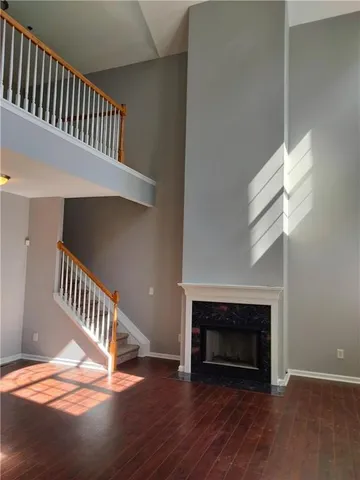 a view of an empty room with wooden floor stairs and a fireplace