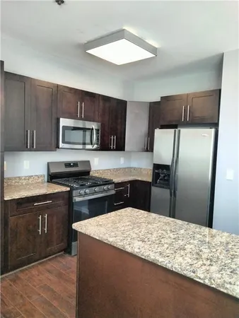 a kitchen with stainless steel appliances granite countertop a sink refrigerator and cabinets