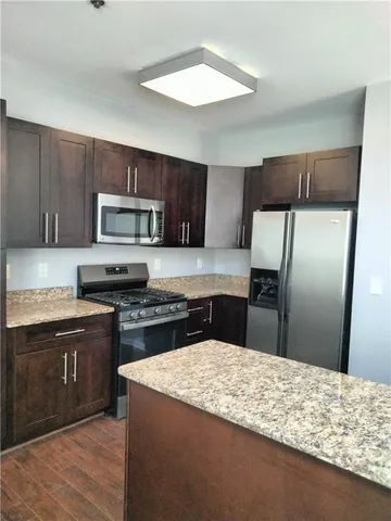 a kitchen with stainless steel appliances granite countertop a sink refrigerator and cabinets