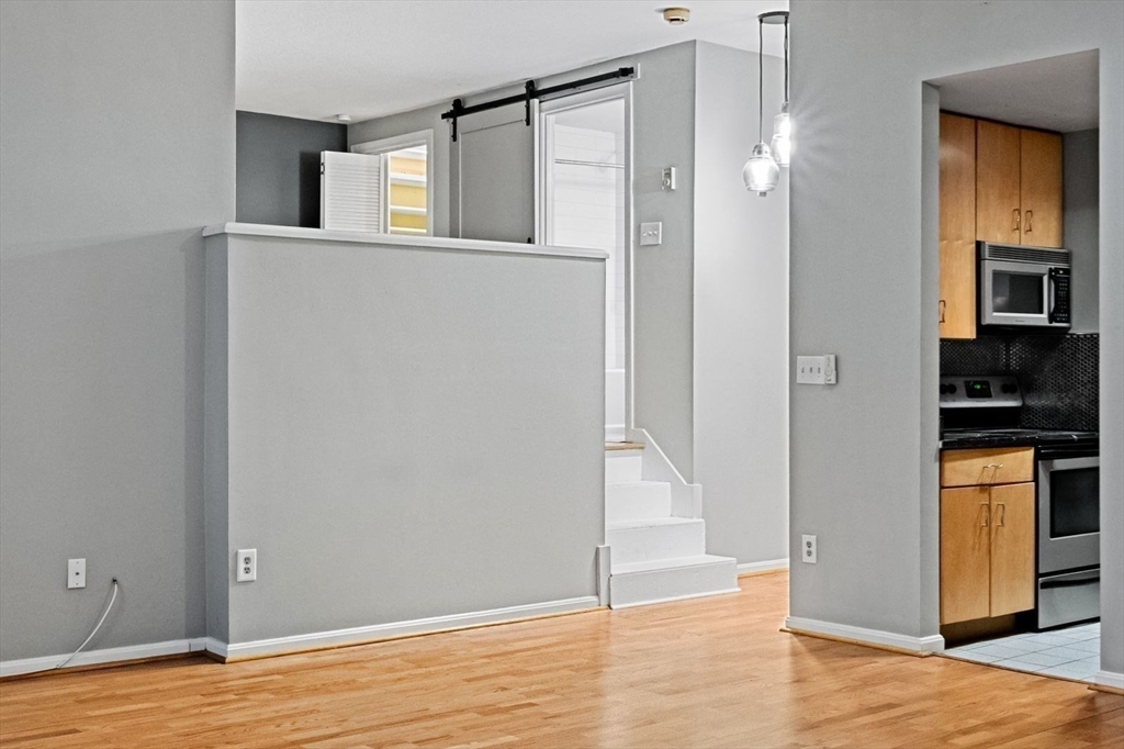 350 West Fourth Street, Unit 103 Boston, MA 02127 - Photo 10 of 33 a view of an empty room with kitchen and wooden floor
