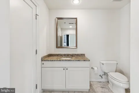 a bathroom with a granite countertop toilet sink and mirror
