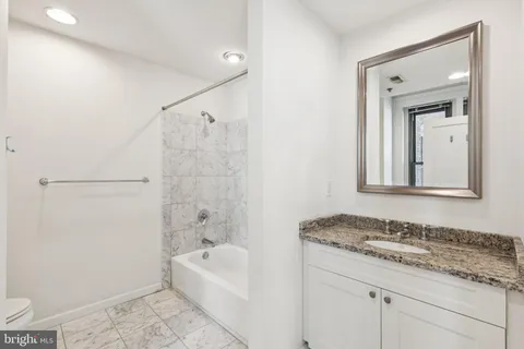 a bathroom with a granite countertop sink mirror vanity and bathtub