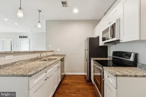 a kitchen with granite countertop cabinets stainless steel appliances and a counter space