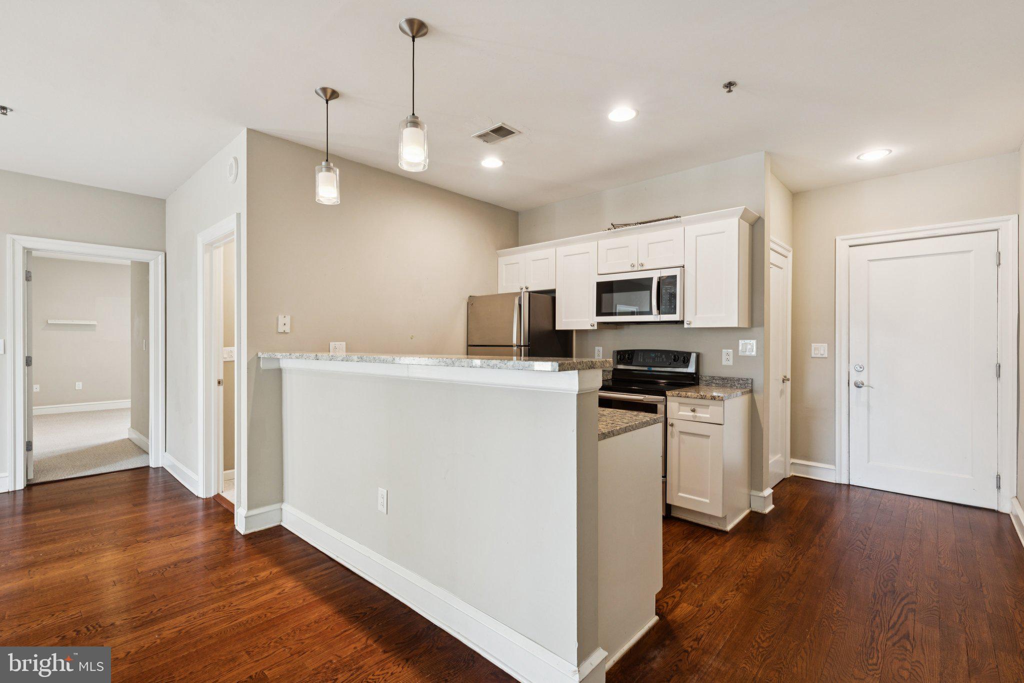 1811 Chestnut Street, Unit 701 Philadelphia, PA 19103 - Photo 6 of 26 a kitchen with stainless steel appliances granite countertop a refrigerator a stove top oven a sink and dishwasher with wooden floor