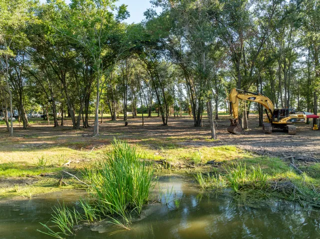 a view of a swimming pool with a yard and large trees