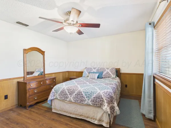 a bedroom with a bed and a dresser with wooden floor