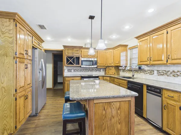 a kitchen with stainless steel appliances granite countertop a sink a stove and a refrigerator