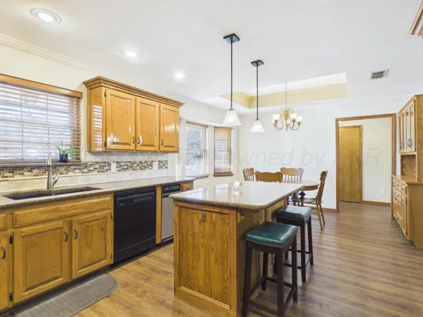 a dining table with stainless steel appliances granite countertop a kitchen island a stove and a sink