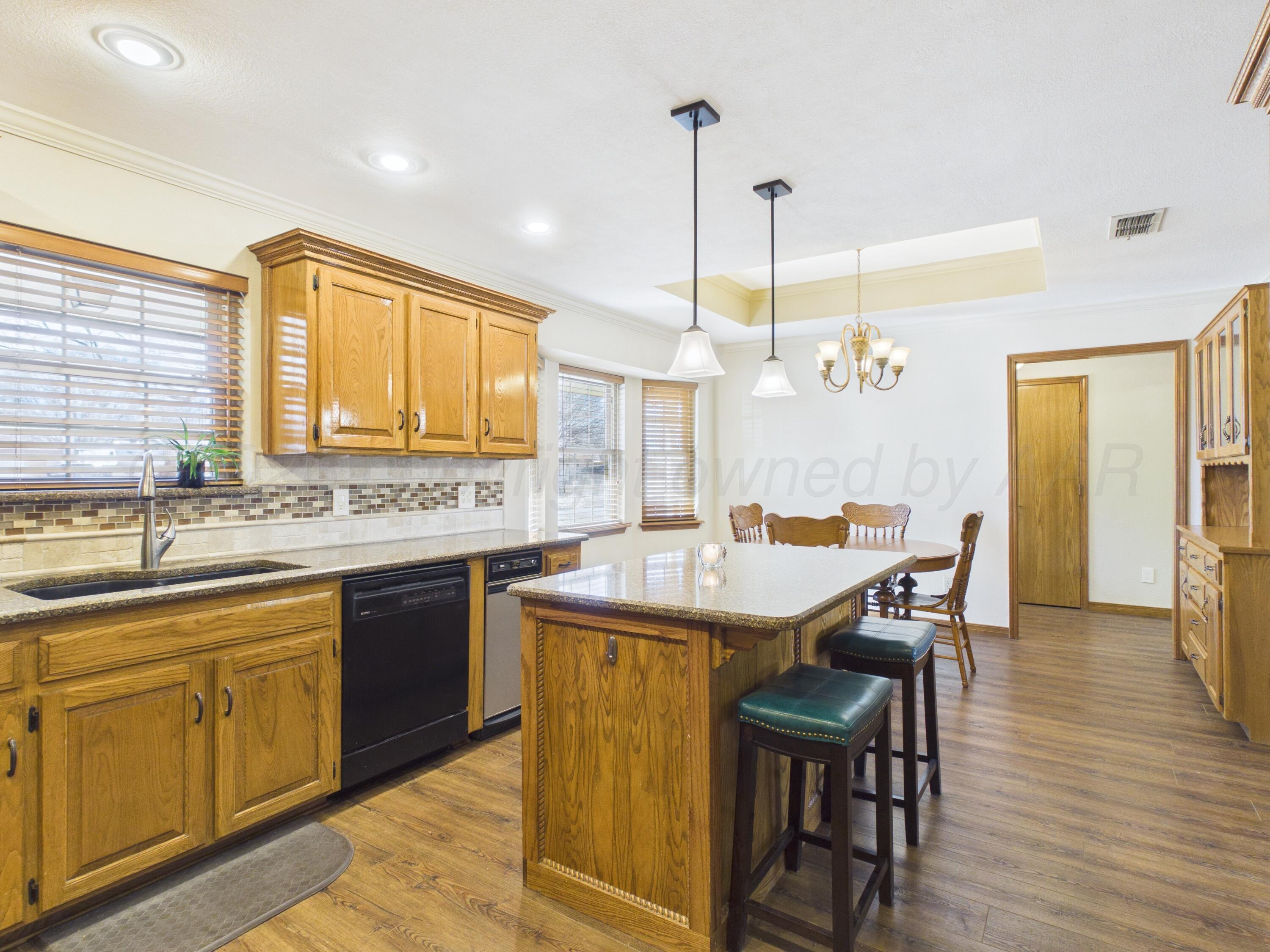 506 Robin Road Dumas, TX 79029 - Photo 5 of 31 a dining table with stainless steel appliances granite countertop a kitchen island a stove and a sink