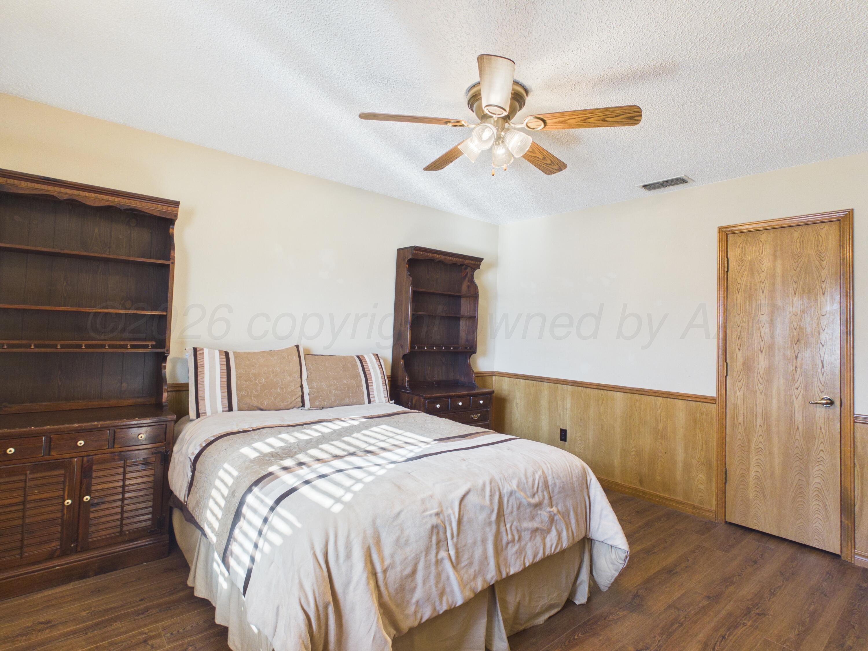 506 Robin Road Dumas, TX 79029 - Photo 8 of 31 a bedroom with a bed and a chandelier