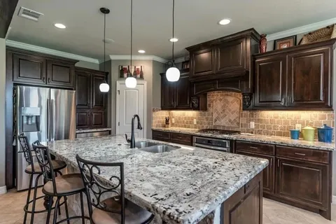 a kitchen with stainless steel appliances granite countertop a stove refrigerator and cabinets