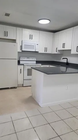 a kitchen with granite countertop a stove a sink and a refrigerator