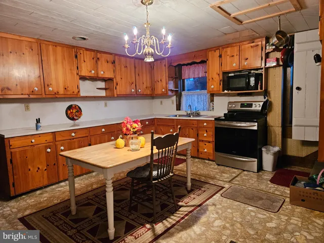 a kitchen with stainless steel appliances granite countertop a stove refrigerator a sink dishwasher a dining table and chairs with wooden floor