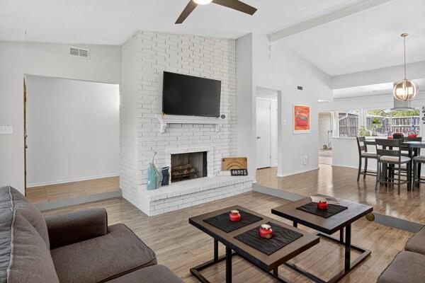 6331 North Jim Miller Road Dallas, TX 75228 - Photo 2 of 28 Living area featuring light wood-style floors, ceiling fan, and a brick fireplace
