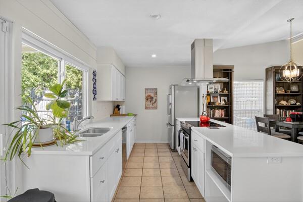 6331 North Jim Miller Road Dallas, TX 75228 - Photo 9 of 28 Kitchen featuring white cabinets, island range hood, appliances with stainless steel finishes, light tile patterned floors, and decorative light fixtures