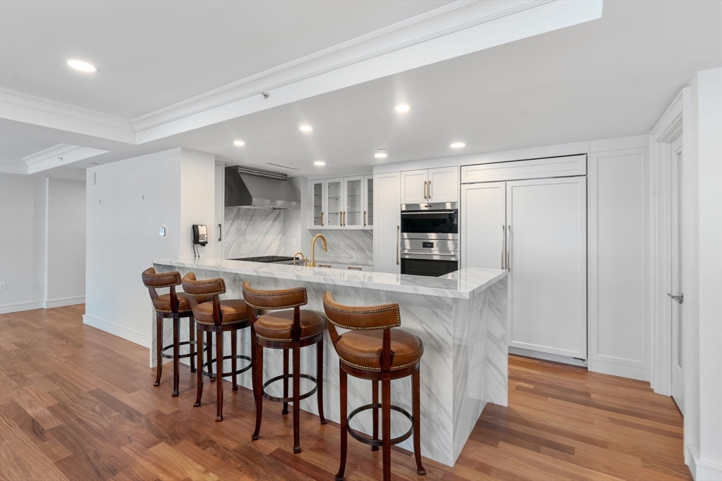 4 Battery Wharf, Unit 4604 Boston, MA 02109 - Photo 12 of 39 a kitchen with stainless steel appliances granite countertop a table chairs sink and cabinets