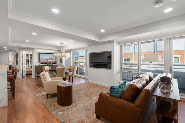 a view of a livingroom with a flat screen tv wooden floor and kitchen